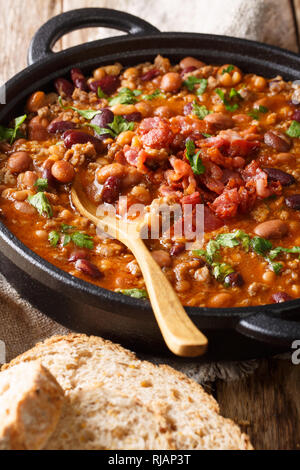 cowboy beans with ground beef, bacon and herbs close-up on the table. vertical Stock Photo