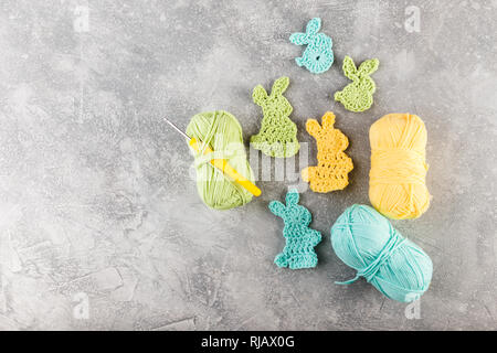 Easter decoration, bunny rabbits made of crochet colorful yarn ongrey texture background. Homemade decor. Top view. Spring Easter holydays concept. Stock Photo