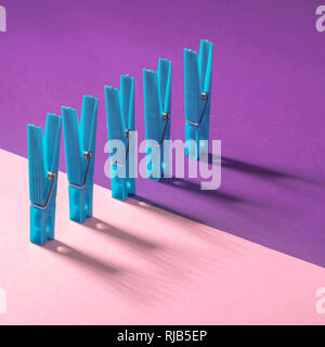 Blue clothespins on a pink purple background. Modern conceptual art. Stock Photo