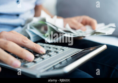 closeup of a caucasian man with a pile of bills and tickets in his hand using an electronic calculator to do some accounts Stock Photo