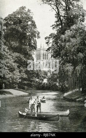 Two young men punting in canoes on the River Cam at Cambridge, with St John's Chapel in the background.
