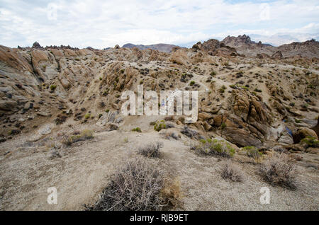 Woman hiker walks along a dirt trail through the Alabama Hills to the The Mobius Arch Loop Trailhead Stock Photo