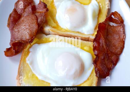 Two poached eggs with bacon on white buttered toast Stock Photo