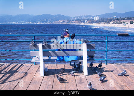 Santa Monica, California.  October 12, 2017.  A woman sitting on a bench on the santa monica pier overlooking the pacific ocean and beach covered in p Stock Photo