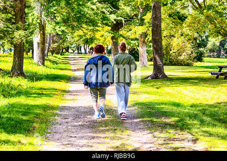 Litchfield, Connecticut.  September 9, 2017.  A grandmother and granddaughter holding hands walking down a path within Topsmead State Park in Litchfie Stock Photo