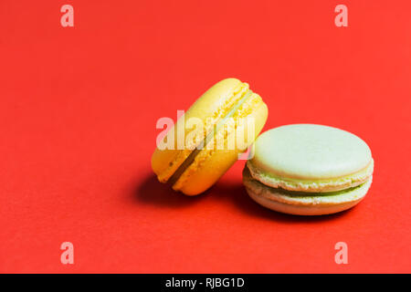 Closeup of two green and yellow French macaroons on a red background Stock Photo