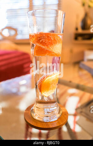 Clear water in clean glass with super color orange crispy bubbles. Lifestyle Room Background. Stock Photo