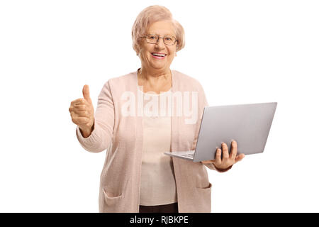 Happy senior woman holding a laptop computer and showing thumbs up isolated on white background Stock Photo