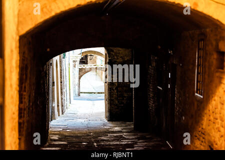 Siena, Italy dark narrow alley street in historic medieval old town village in Tuscany with nobody and arch passage Stock Photo