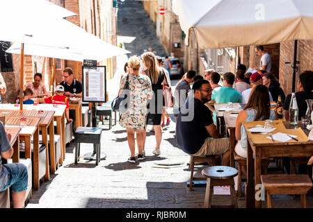 Siena, Italy - August 27, 2018: Alley street called Costa Sant'Antonio in historic medieval old town village in Tuscany with tourists people walking b Stock Photo