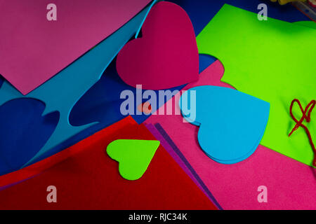 Hearts cut out of bright color foam sheets viewed in full frame background. Bright green and red hearts on blue sheet viewed from above. Love and rela Stock Photo