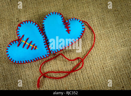 Valentine Day template, two handmade blue foam sheet stitched toy hearts on jute canvas, close up, high angle view. Love, relationship, Valentines Day Stock Photo