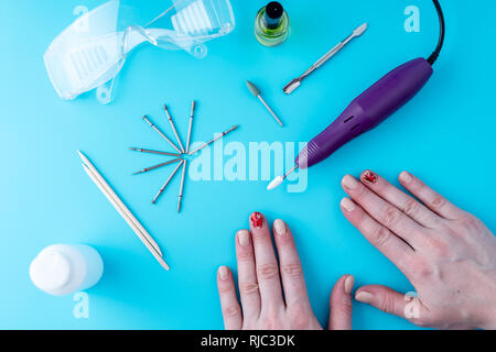 Tools for professional hardware manicure and women's hands with manicure on blue background Stock Photo