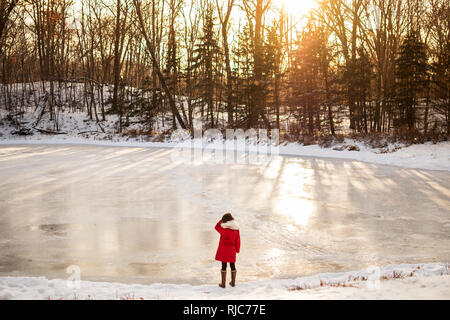 Girl standing in front of a frozen lake in winter, United States Stock Photo