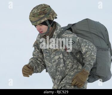 Army Pvt. Conner Langley, a native of Baton Rouge, La., assigned to the 6th Brigade Engineer Battalion, 4th Infantry Brigade Combat Team (Airborne), 25th Infantry Division, U.S. Army Alaska, proceeds the rally point after completing his first airborne training jump at Malemute drop zone, Joint Base Elmendorf-Richardson, Alaska, Jan. 9, 2018. The Soldiers of 4/25 belong to the only American airborne brigade in the Pacific and are trained to execute airborne maneuvers in extreme cold weather/high altitude environments in support of combat, training and disaster relief operations. Stock Photo