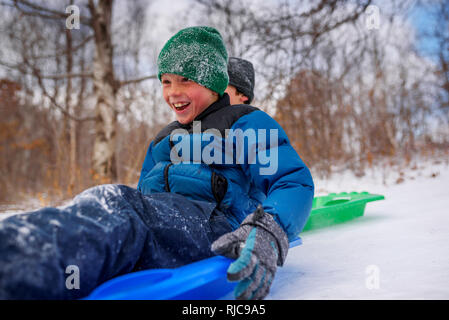 Two boys on a sledge laughing, Wisconsin, United States Stock Photo