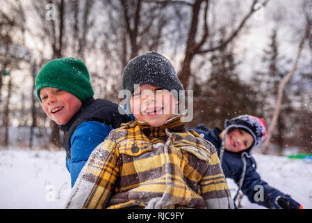 Three children messing about in the snow, Wisconsin, United States Stock Photo