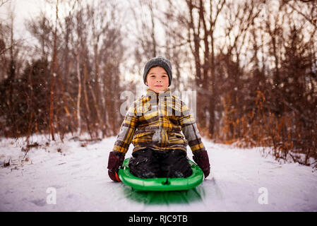 Boy sitting on a sledge, Wisconsin, United States Stock Photo