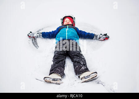 Boy lying in snow making a snow angel, Wisconsin, United States Stock Photo