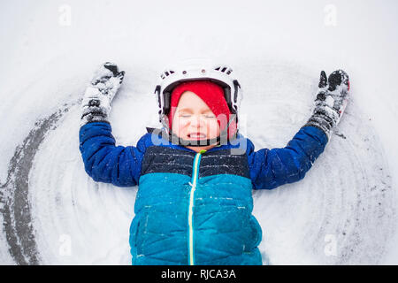 Boy lying on frozen lake making a snow angel, Wisconsin, United States Stock Photo