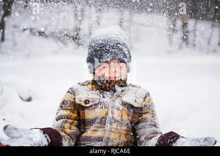 Boy standing in a snow storm catching  snowflakes, Wisconsin, United States Stock Photo