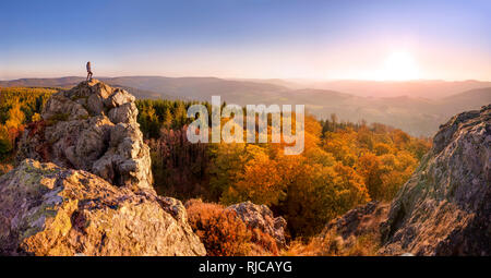 Young woman enjoying the view from high lookout of the Bruchhauser Steine (Feldstein), Bruchhausen, into the beautiful Sauerland in fall. Germany. Stock Photo