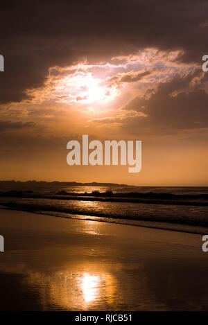 Majestic view of cloudy evening sky over wonderful waving sea and wet sandy coast in Ribadeo, Spain Stock Photo