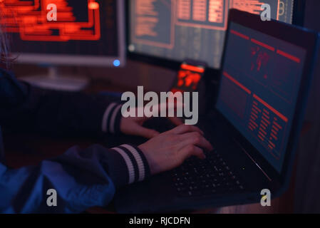 The hands of a Hacker typing program code, hacking a firewall system on the background of the screens in the dark under neon light. The concept of cyb Stock Photo