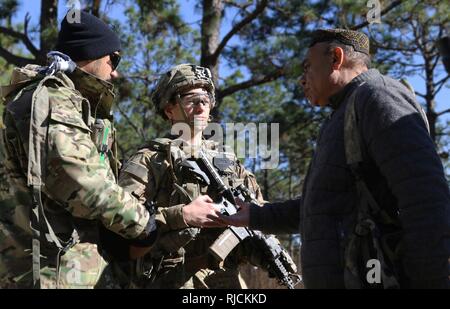 Afghan National Defense Security Forces role players talk to Capt. Justin Alexander, a combat team advisor team leader assigned to the 1st Security Force Assistance Brigade during a simulated event at the Joint Readiness Training Center at Fort Polk, La., Jan. 13, 2018. The JRTC rotation was conducted in order to prepare the newly formed 1st SFAB for an upcoming deployment to Afghanistan in the spring of 2018. SFAB’s provide combat advising capability while enabling brigade combat teams to prepare for decisive action, improving readiness of the Army and its partners. Stock Photo