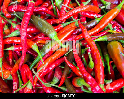 Multi-colored hot peppers are scattered on the table Stock Photo