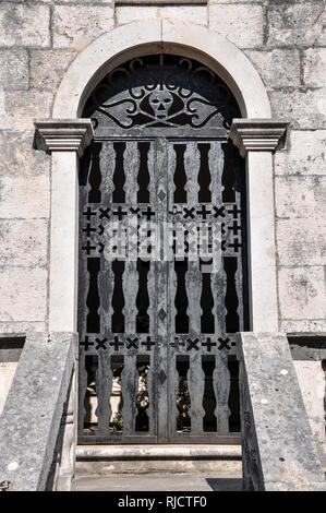 An ornate metal gate featuring a stylised skull at the entrance to a tomb in the cemetery of Our Lady of the Angels Monastery, Podgorje, Croatia Stock Photo