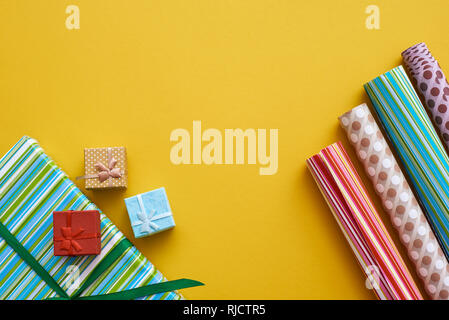 Gift packaging. Bright and colorful gift wrap rolls on yellow background. Stock Photo