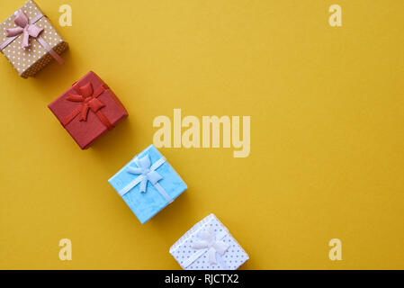 Little gift boxes in different colors on yellow background Stock Photo