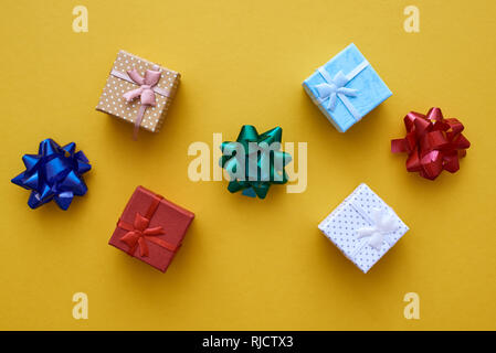 For friends. Small Gift Boxes with Colorful Bows on yellow background Stock Photo