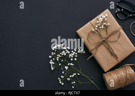 Design Your Gift Beautiful gift box in kraft brown paper on dark background and wrapping accessories. Stock Photo