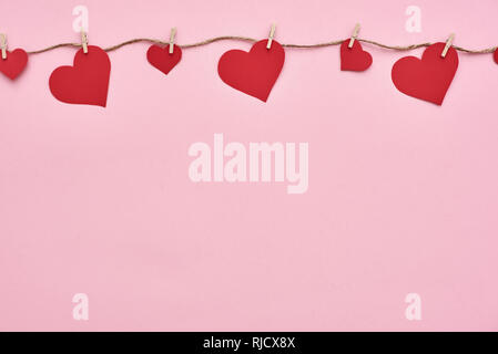 Valentine day...Red paper hearts hanging on the clothesline on pink background Stock Photo