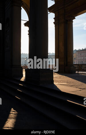 Early morning sunlight casting long shadows through the columns of the entrance to the Uffizi Gallery on the banks of the River Arno Florence Italy Stock Photo