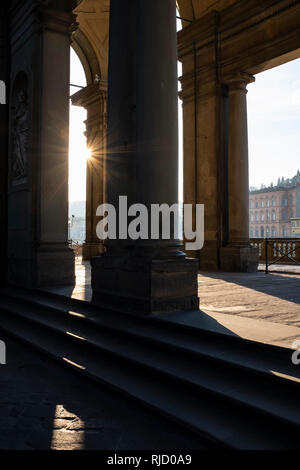 Early morning sunlight casting long shadows through the columns of the entrance to the Uffizi Gallery on the banks of the River Arno Florence Italy Stock Photo