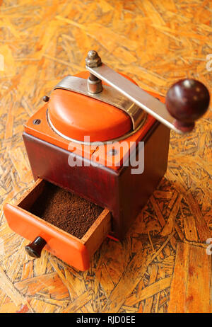 Ground coffee in the vibrant color retro coffee grinder ready for homemade coffee Stock Photo