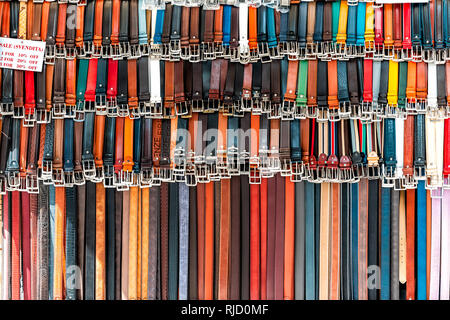 Florence, Italy - August 30, 2018: Closeup pattern of many belts leather colorful vibrant colors hanging on display with sale sign in shopping street  Stock Photo