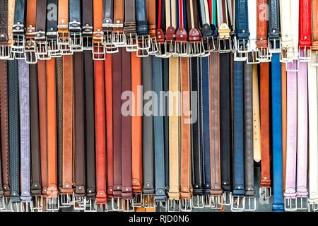 Florence, Italy - August 30, 2018: Closeup pattern of many belts leather colorful vibrant colors hanging on display in shopping street market in Firen Stock Photo