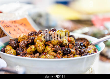 Green mixed olives many closeup in Florence Italy central market in bowl with sign and spoon scoop Stock Photo
