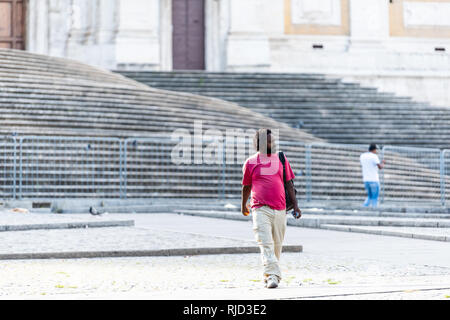 Rome, Italy - September 4, 2018: African refugee homeless man walking in city park by Obelisco Esquilino in piazza square Stock Photo