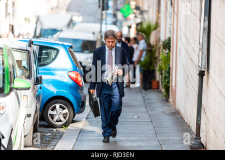 Rome, Italy - September 4, 2018: One local Italian man in city street work businessman walking on sidewalk in business office suit reading newspaper Stock Photo