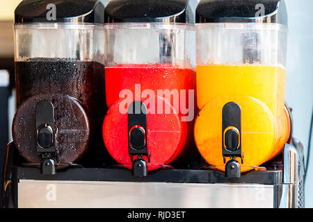 Three machines closeup of slush slushie cold drinks with slushy ice and colorful colors for refreshing summer with black, red and yellow Stock Photo