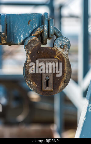 Old rusty padlock high on the Famous Transporter Bridge, Newport Wales UK  with peeling industrial blue paint daytime and close up shot. Stock Photo