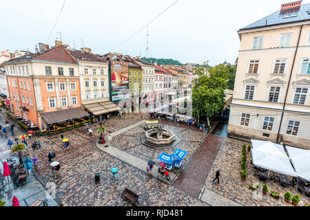 Lviv, Ukraine - July 31, 2018: Aerial high angle view of historic Ukrainian city in old town market square with cafe restaurant water fountain in wet  Stock Photo