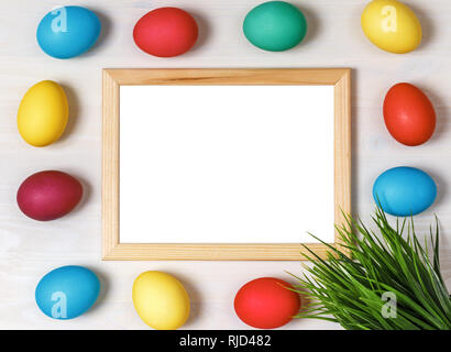 Multi-colored eggs and artificial green grass around the frame on a white background. Easter concept. Copy space Stock Photo