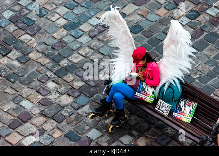 Lviv, Ukraine - July 31, 2018: Aerial high angle above view of old town market square and woman angel wings sitting on bench advertisement for tattoo Stock Photo