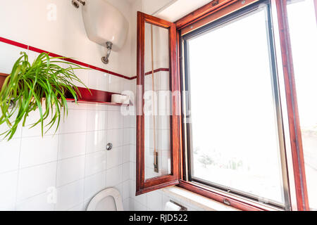 White clean toilet bathroom with red color wooden window frame tiles tiled wall in Italian style apartment villa home house in Tuscany, Italy Stock Photo